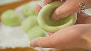 將均分的艾草面團(tuán)搓成圓，挖一個(gè)窩，放入餡心，再搓成圓。