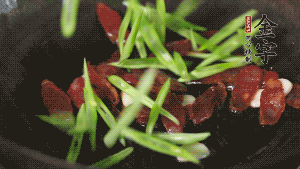 先后下香腸片、四季豆絲均勻翻炒，加適量清水燜煮一下。