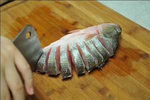 將鱸魚(yú)清洗干凈，從脊椎處切斷至腹部，腹部保留1cm左右不要切斷。