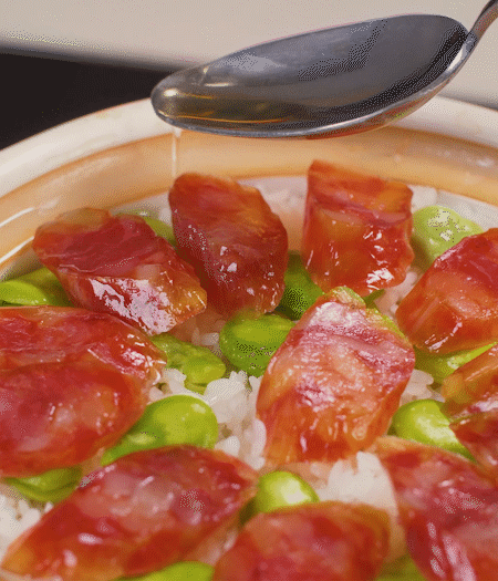 大米出現(xiàn)小孔時(shí)開蓋放香腸，往鍋邊淋入少許油，再燜煮8~10分鐘左右。