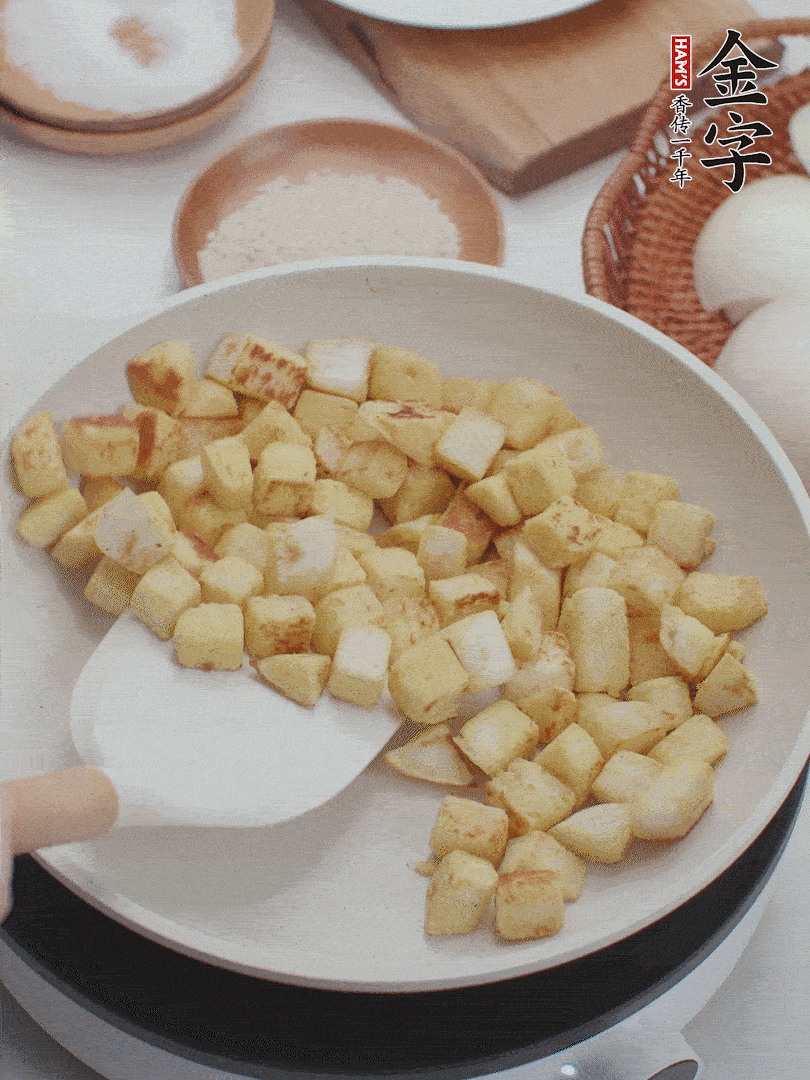 起鍋熱油，倒入饅頭丁，小火煎至蛋液凝固定型再翻面，饅頭丁部煎至金黃時(shí)盛起待用。